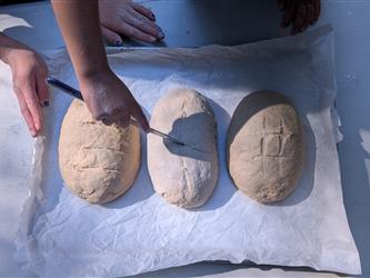 Small hands cutting grooves into dough loaves